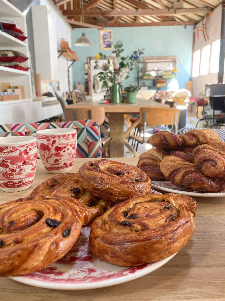 Gezellige interieurfoto met verse croissants, koffie en bloemen, ideaal voor passie voor horeca en bakkerijen.