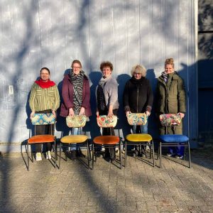 Gezellige dames met kleurrijke stoelen en mode in een creatieve buiten setting.