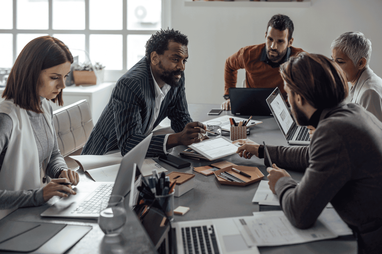 Focused business team collaborating around a table in a modern office to achieve outcome-driven results for strategic success.