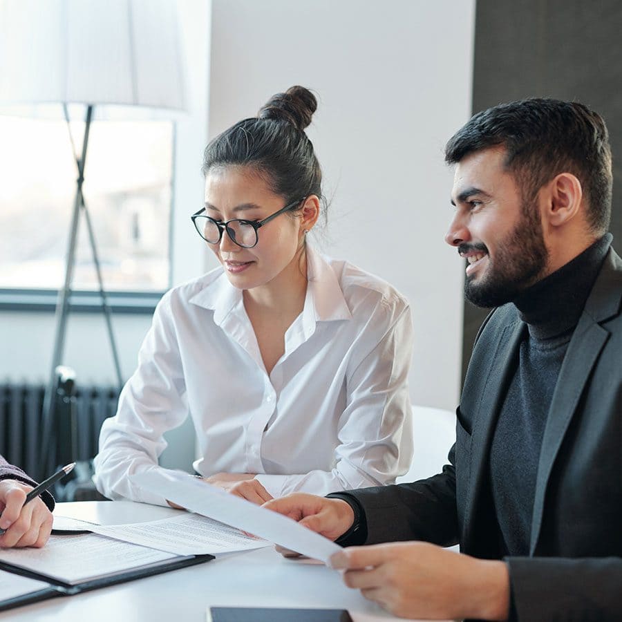 Clear business meeting with diverse professionals reviewing documents, emphasizing outcome-driven strategies and solutions for organizational success.