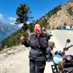 Woman enjoying mountain ride with motorcycle and scenic mountain background.