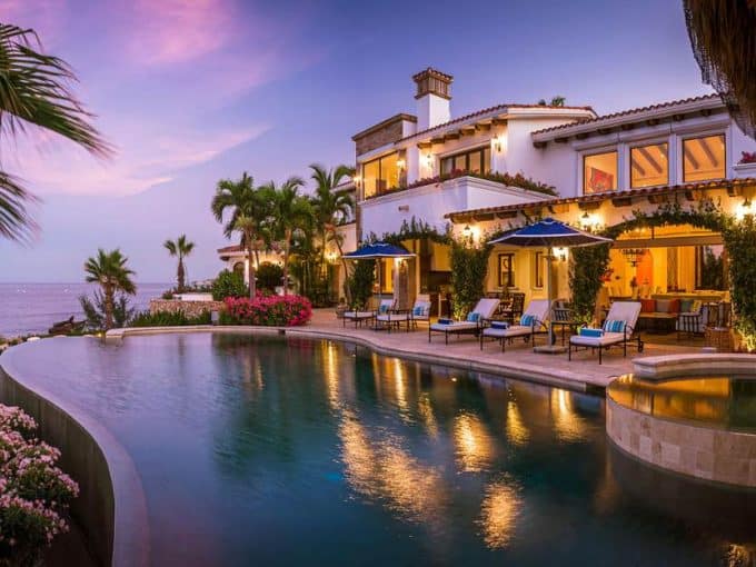 A Pool With A House And Palm Trees