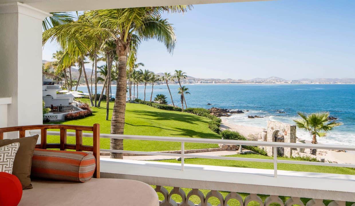 Palmilla Beach View With Lush Green Lawns, Tall Palm Trees, And The Ocean Horizon From A Seaside Balcony In A Luxurious Property.
