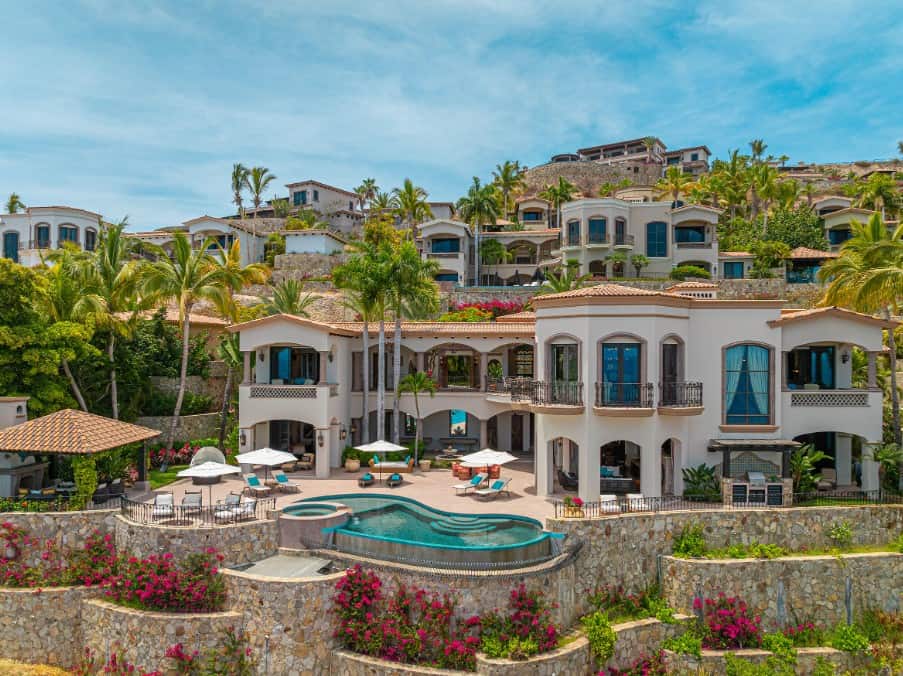 A Stunning Custom Luxury Home In Palmilla Featuring Mediterranean Architecture, Private Infinity Pool, And Lush Landscaping, Surrounded By Upscale Hillside Residences.