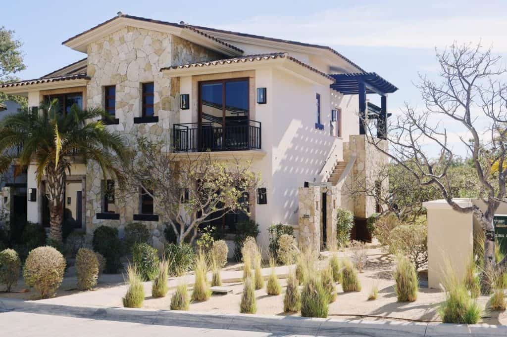 Luxury Palmilla Home With Stone Façade, Modern Design, And Landscaped Desert Garden. Features A Balcony, Large Windows, And Elegant Outdoor Lighting In A Serene Neighborhood.