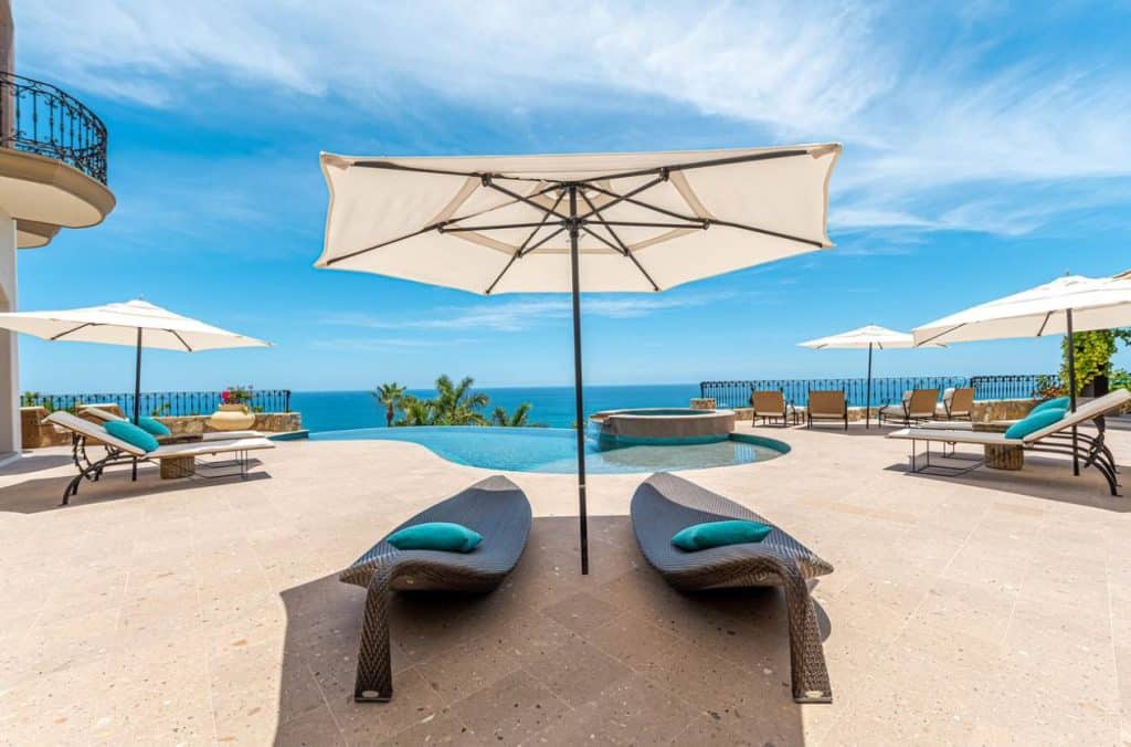 Luxury Terrace With Infinity Pool, Lounge Chairs, And Umbrellas Overlooking The Sea Of Cortez At An Exclusive House In Palmilla For Sale.