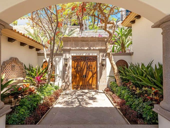 Luxury Courtyard Entrance With Wooden Doors And Tropical Landscaping At Hacienda 505, Villas Del Mar Palmilla, San Jose Corridor Real Estate.