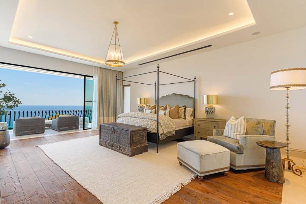 Elegant Master Bedroom At La Montaña 7 In Villas Del Mar, Palmilla, Featuring A Four-Poster Bed, Luxury Furnishings, Hardwood Floors, And Balcony With Panoramic Views Of The Sea Of Cortez In Los Cabos.