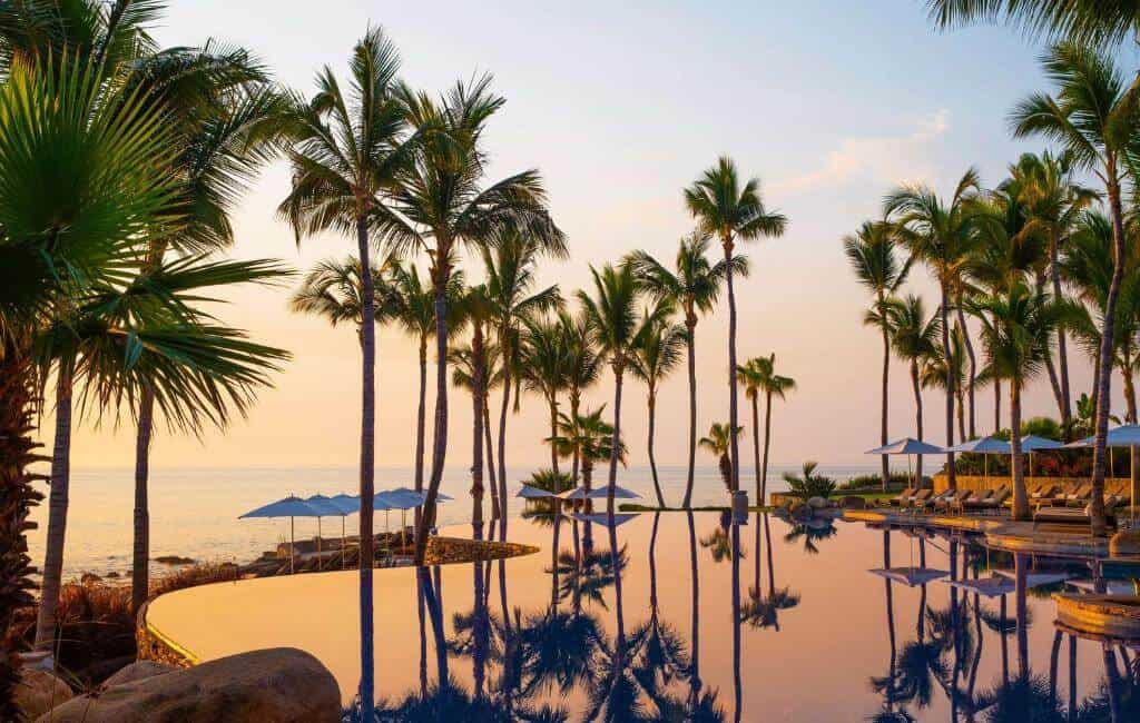 Infinity Pool Surrounded By Palm Trees At One&Amp;Only Palmilla Los Cabos During Sunset.