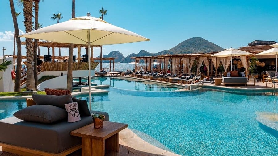 Relaxing Poolside Scene At Palmilla, With Lounge Chairs, Umbrellas, And Ocean Views, Perfect For Luxury Resort Guests Seeking Comfort And Tranquility In Palmilla.