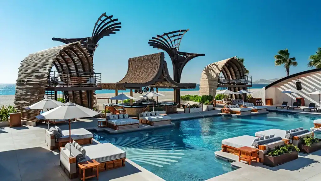 Luxurious Palmilla Beachfront Pool With Modern Cabanas, Lounge Chairs, And Ocean Views At Palmilla Real Estate. Perfect For Relaxing And Enjoying Seaside Tranquility.