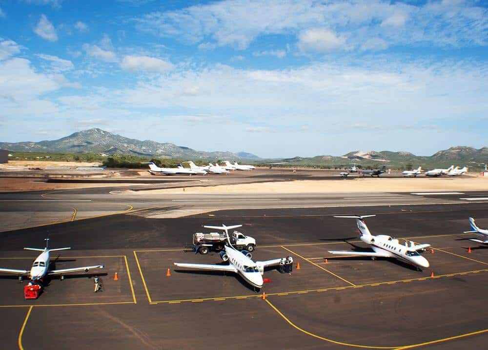 Private Jets Parked On The Runway At Cabo Mexico Airport With Mountain Views In The Background.