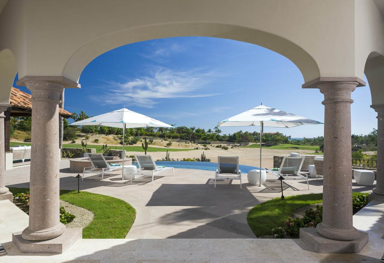 Luxurious Palmilla Estate With Stunning Outdoor Pool View, Lounge Chairs, And Shaded Umbrellas Under Bright Blue Skies, Perfect For Relaxing Or Enjoying The Scenic Golf Course And Desert Landscape.