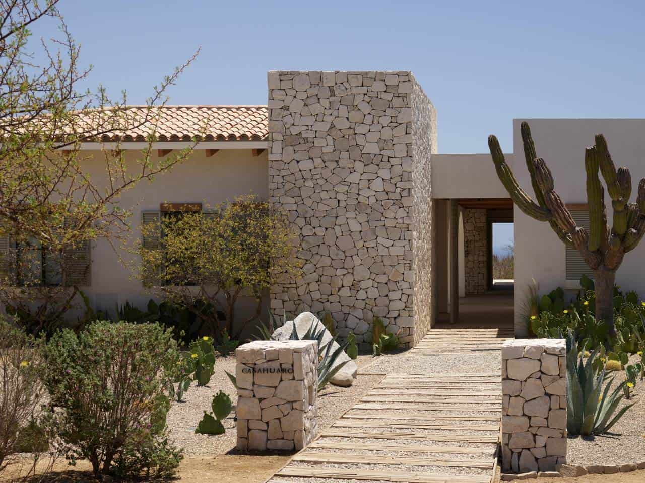 Elegant Palmilla Real Estate Property With Desert Landscaping, Stone Accents, And A Modern Architectural Design Under A Clear Blue Sky.