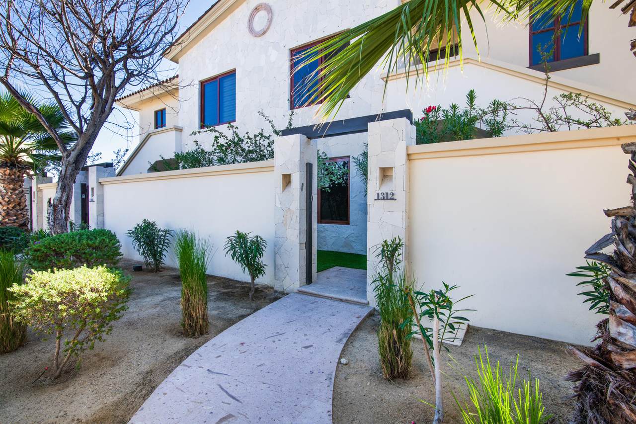 Elegant Palmilla Residence With Modern Design, Pristine White Exterior, Landscaped Front Garden, And Inviting Entryway For Luxury Living.