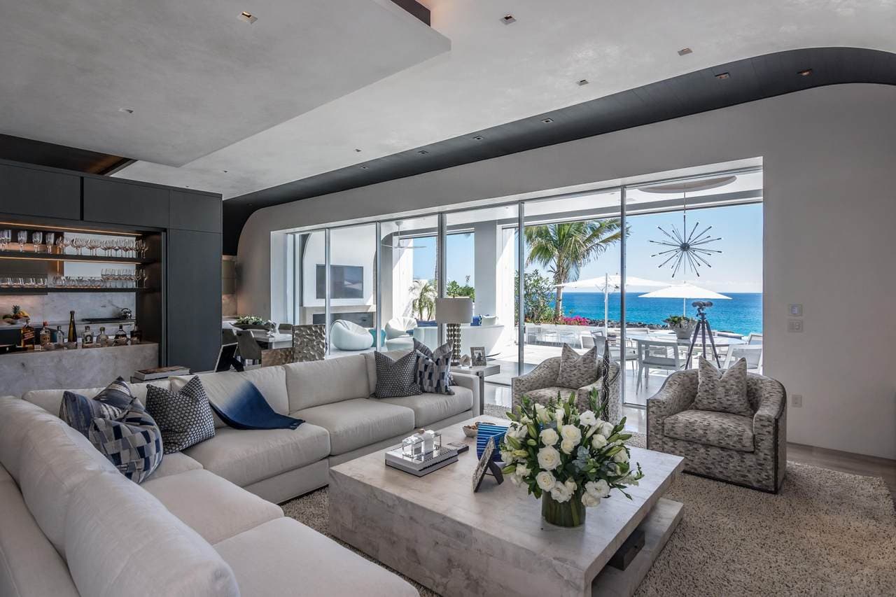 Palmilla Oceanview Living Room With Modern Decor And Large Windows Showcasing The Stunning Cabo Coastline.
