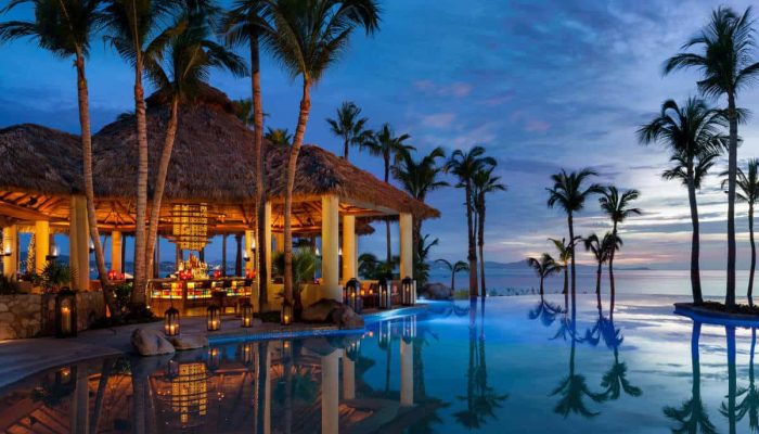 Luxurious Palmilla Resort With Thatched Roof Cabana, Tropical Palm Trees, And Infinity Pool Overlooking The Ocean, Perfect For Exclusive Real Estate Experiences In Palmilla.