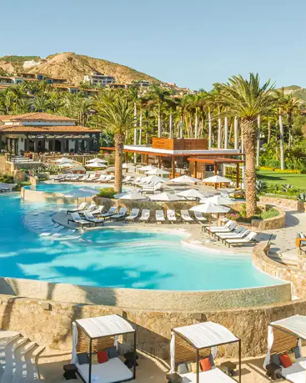 Palmilla Fitness And Wellness Luxury Palmilla Fitness And Wellness Resort Pool Area With Lounging Chairs, Umbrellas, Palm Trees, And Hillside Residences.