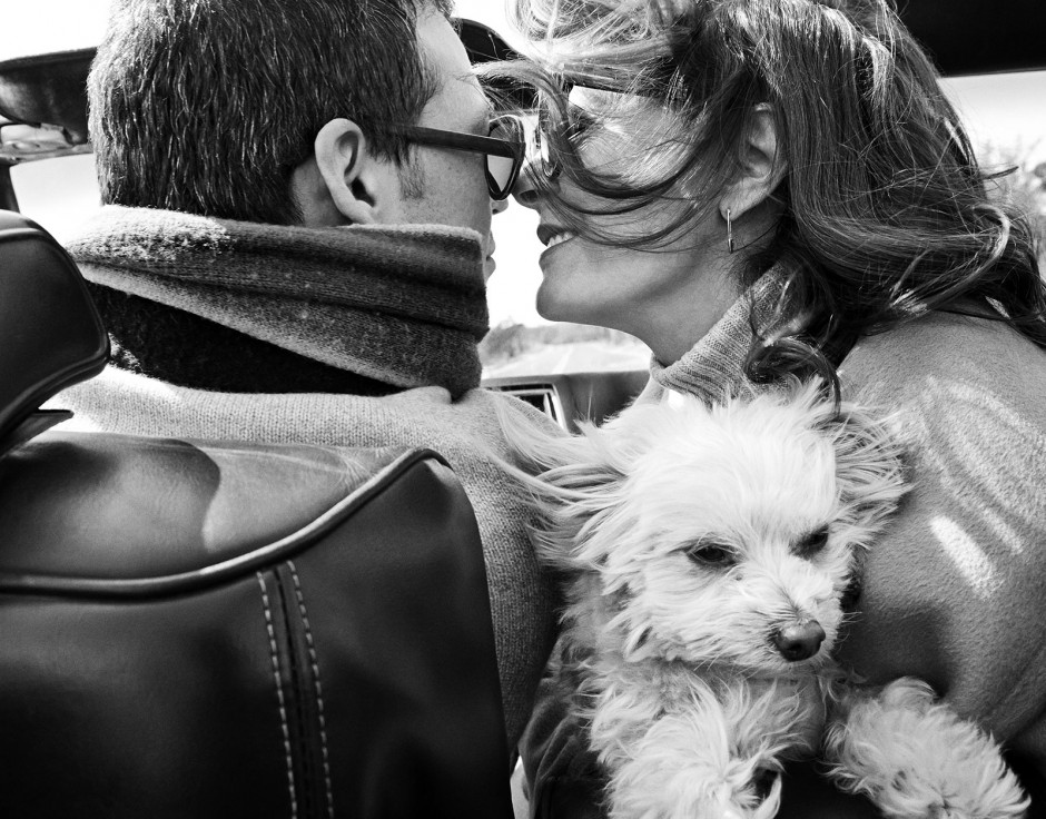Romantic couple in convertible car with dog, black and white photo, intimate moment, travel photography, lifestyle photography, Pamela Hanson Photography, emotional connection, outdoor scene.