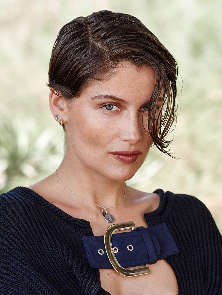 Elegant portrait of a young woman with short dark hair, blue eyes, and subtle makeup, wearing a navy sweater with statement buckle detail, dainty jewelry, captured in natural lighting by Pamela Hanson Photography.