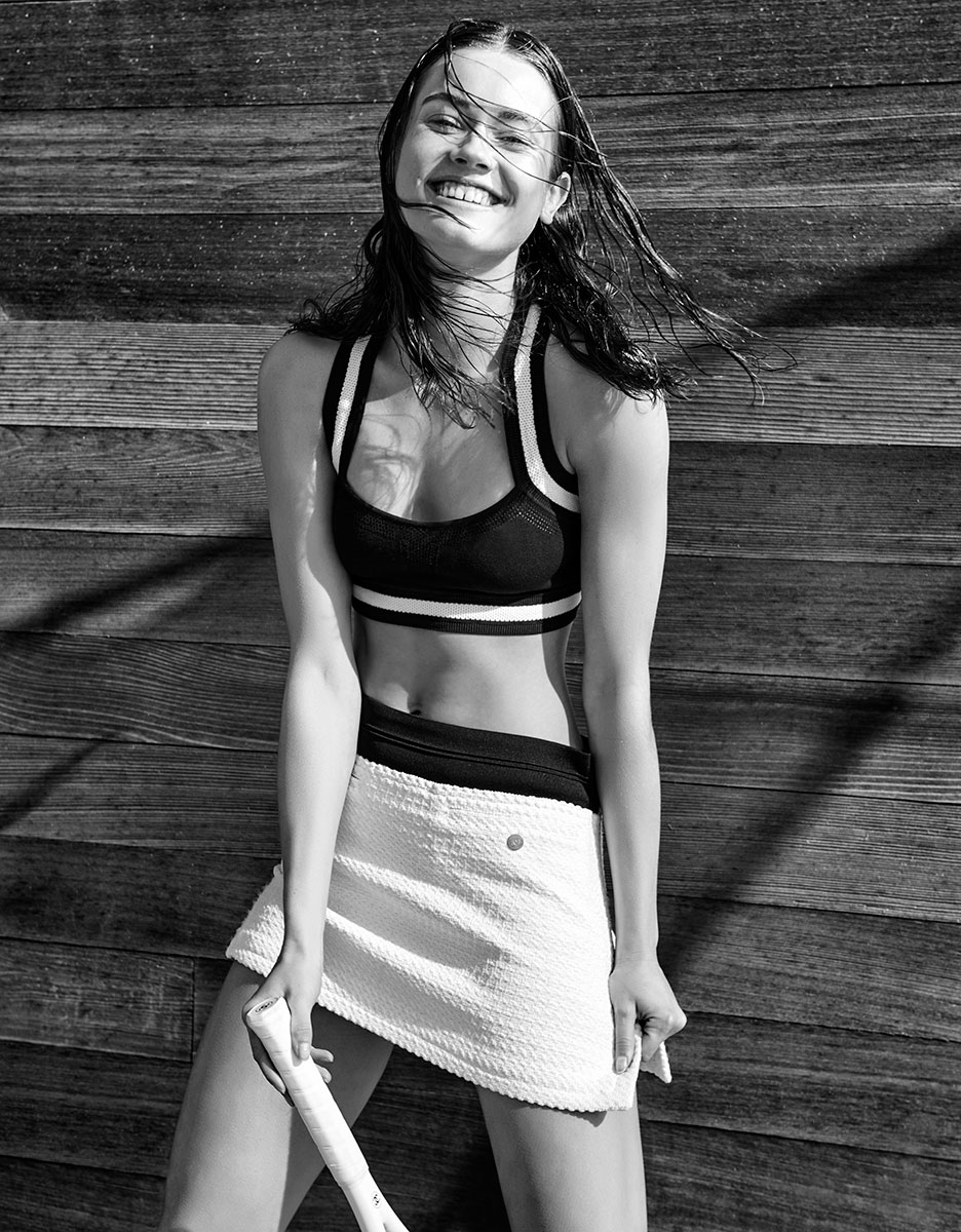 Playful young woman smiling outdoor tennis player black and white photograph, athletic sportswear, natural light, wooden background, happy lifestyle, dynamic lifestyle photography, Pamela Hanson Photography.
