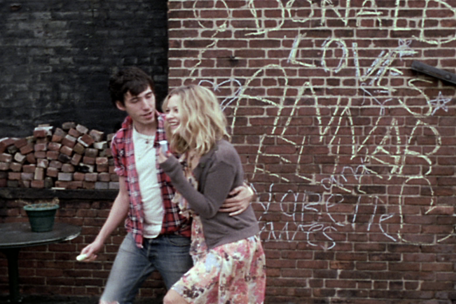 Young couple dancing outdoors in an urban setting, graffiti art on brick wall, casual style, romantic and playful moment, street photography, vibrant colors, candid shot.