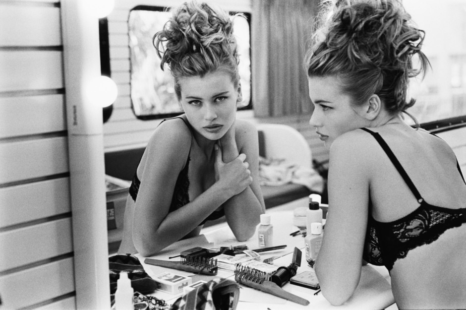 Editorial black and white portrait of a glamorous woman with curly hair in lingerie preparing for photoshoot, makeup, beauty, fashion photography, Pamela Hanson Photography, black and white studio shot.