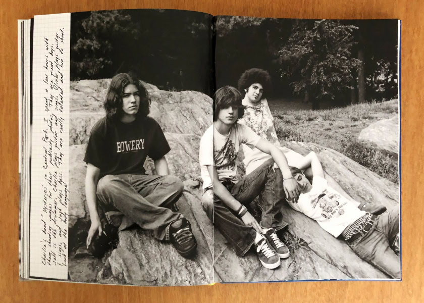 Young group of friends sitting on rocks in a park, casual fashion, black and white photography, outdoors, expressive of youth and friendship, styled to highlight natural poses and candid moments.