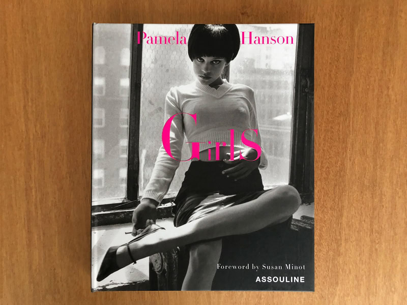 Vintage black and white photograph of a girl sitting by a window, with text overlay for Pamela Hanson Girls photo book, showcasing her photographic style focused on fashion and women's portraiture.