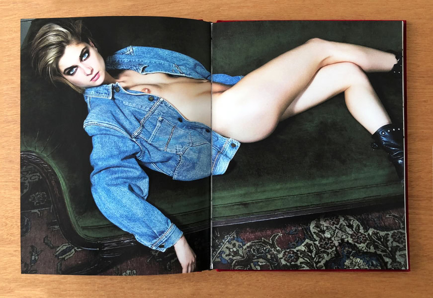 Sensual woman posing nude on green velvet sofa wearing oversized denim jacket, black ankle boots, beautiful blonde hair, intense blue eyes, fashion photography.