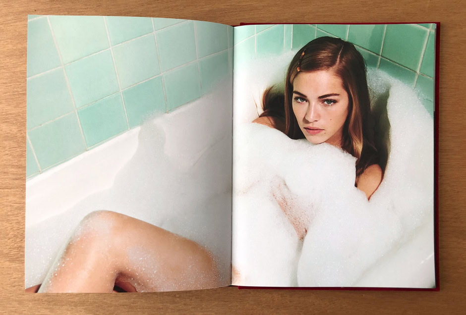 Beautiful young woman with long brown hair relaxed in a bubble bath, green tiled bathroom, sensual and artistic bath portrait, professional photography by Pamela Hanson.