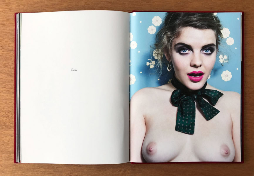 Elegant portrait of a woman with striking blue eyes and bold makeup, featuring behind-the-scenes photography by Pamela Hanson, showcasing artistic nude photography and fashion imagery.