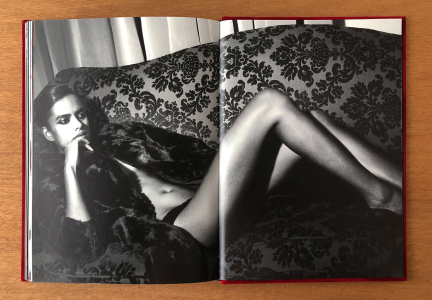 Elegant black and white fashion photography of a woman lounging on a patterned sofa, showcasing sophisticated portraiture by Pamela Hanson, emphasizing style, allure, and artistic expression.