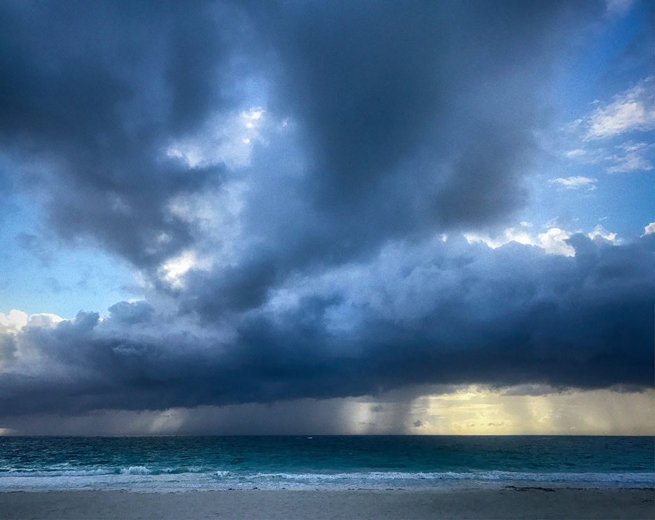 Stormy sky over the ocean with dark clouds and a hint of sunlight, showcasing dramatic weather and seascape photography by Pamela Hanson, perfect for beach and landscape photography portfolios.