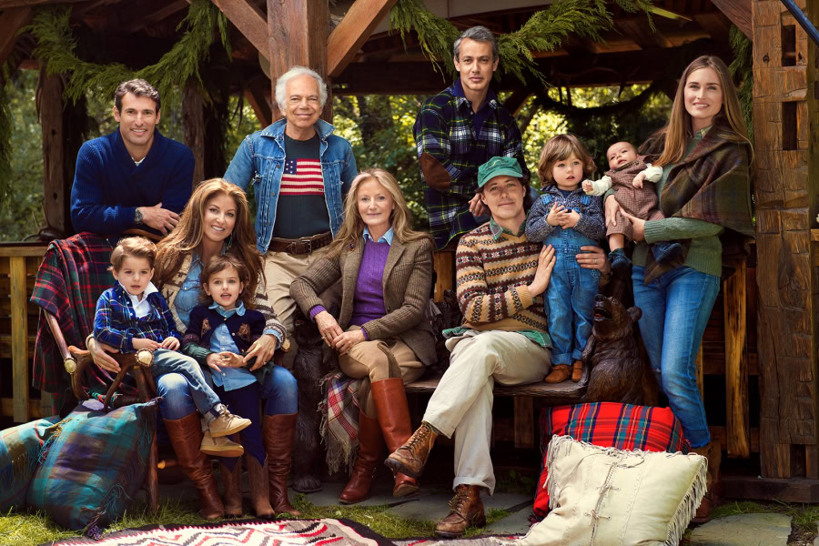 Family outdoor portrait with children and grandparents in rustic cabin setting, autumn clothing, cozy blankets, and greenery. Photographed by Pamela Hanson, capturing warm family moments and candid expressions.