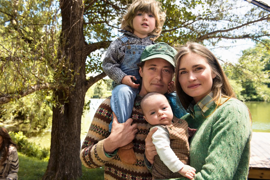Family portrait outdoors by a lake with lush trees, capturing treasured moments with warmth and natural light, showcasing professional photography by Pamela Hanson.