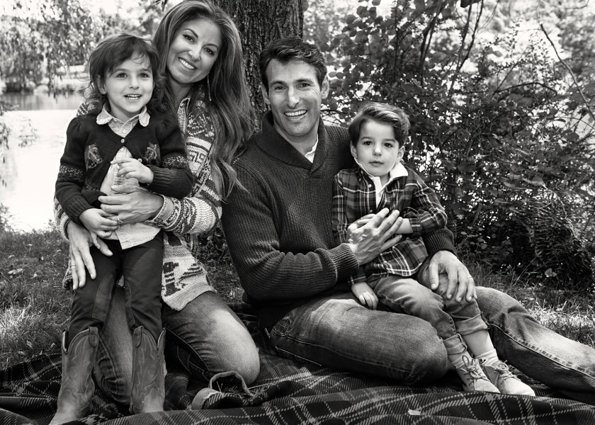 Family portrait outdoors with parents and two children, captured by Pamela Hanson Photography in black and white, showcasing emotional connection and natural setting.