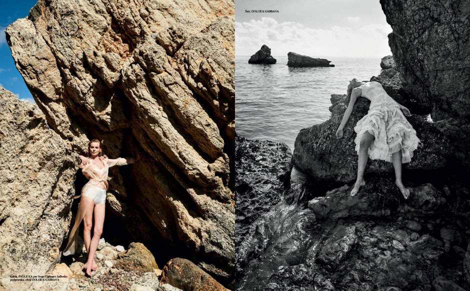 Elegant woman in flowing white dress posing among rugged rocks at the seaside, capturing natural beauty and fashion photography.