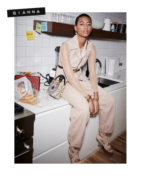 Elegant woman sitting on kitchen counter with stylish beige outfit and accessories, modern home interior photography.