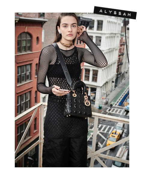 Black fashion model posing on city balcony with designer handbag and street view, urban fashion photography, stylish woman, street style, urban fashion, city life, high-end fashion photography.