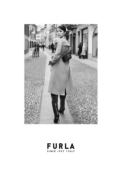 Elegant black and white street fashion photograph featuring a woman in a trench coat and knee-high boots, showcasing luxury fashion and urban style by Pamela Hanson Photography.