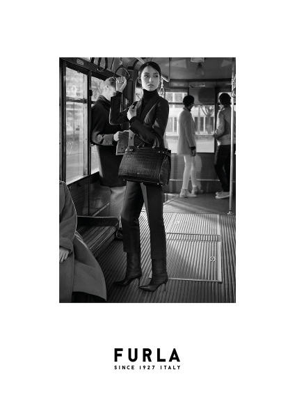 Elegant black and white fashion photograph featuring a stylish woman in a tailored suit and high heels on a city bus, showcasing luxury fashion and urban street style.