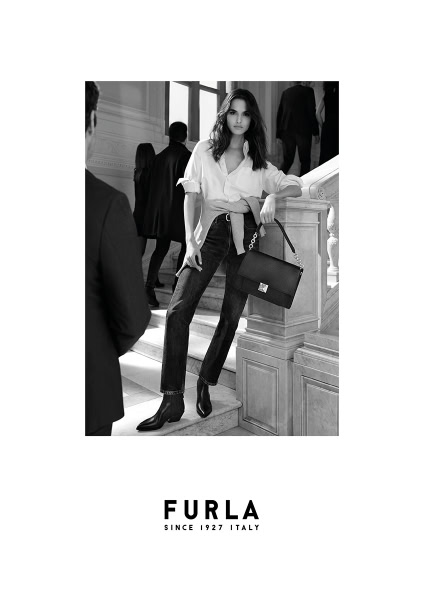 Elegant black and white fashion photography featuring a stylish woman with a Furla handbag, showcasing luxury accessories and high-end fashion in an ornate architectural setting.
