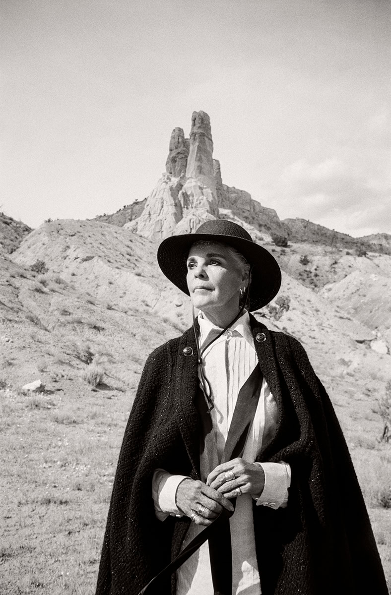 Women in stylish outdoor attire with desert rock formations in background, black and white photography, fashion portrait, Nancy Pelosi style, rugged landscape, glamour, sophistication, timeless elegance, scenic natural setting.