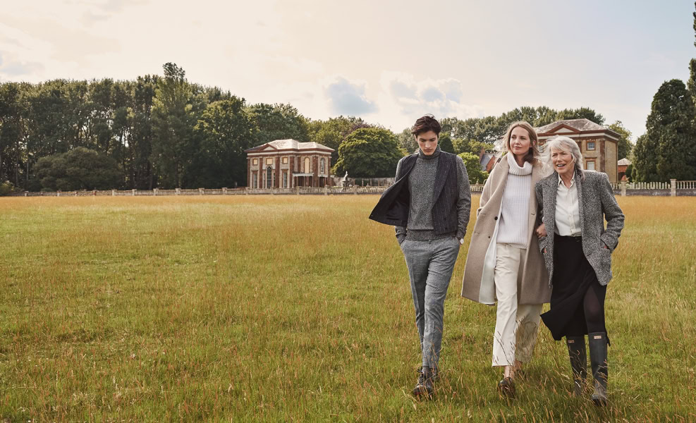 Elegant women walking in a lush park with historic buildings in the background, showcasing fine art fashion photography by Pamela Hanson for sophisticated outdoor portraits and lifestyle imagery.