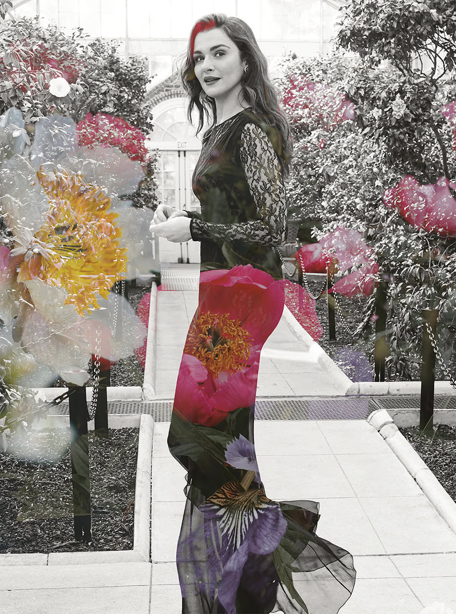 An elegant woman in a black lace dress standing amidst vibrant flowers in a greenhouse, showcasing fine art fashion photography with a focus on floral elements and sophisticated style.