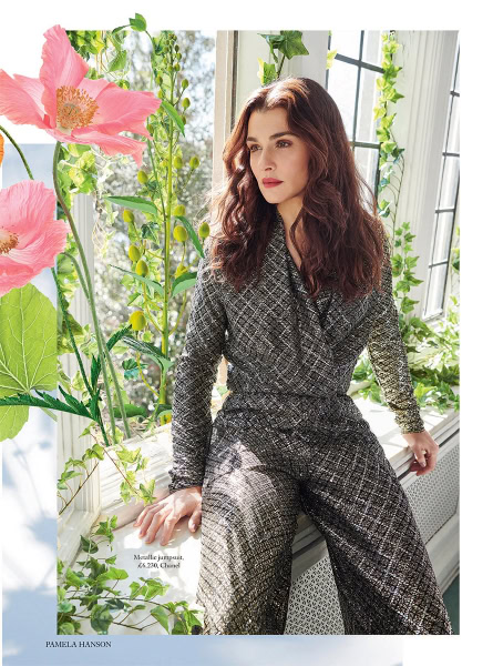 Shutterstock this is a photo of a woman in a metallic jumpsuit sitting on a windowsill with lush green plants and pink flowers in the background, showcasing fashion photography by Pamela Hanson for stylish and elegant looks.