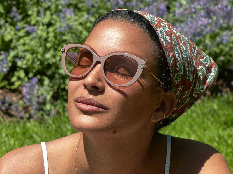 Woman relaxing outdoors in stylish sunglasses with a colorful headscarf, enjoying sunny day, natural beauty, fashion photography, outdoor portrait, summer accessories, trendy eyewear, Pamela Hanson Photography.