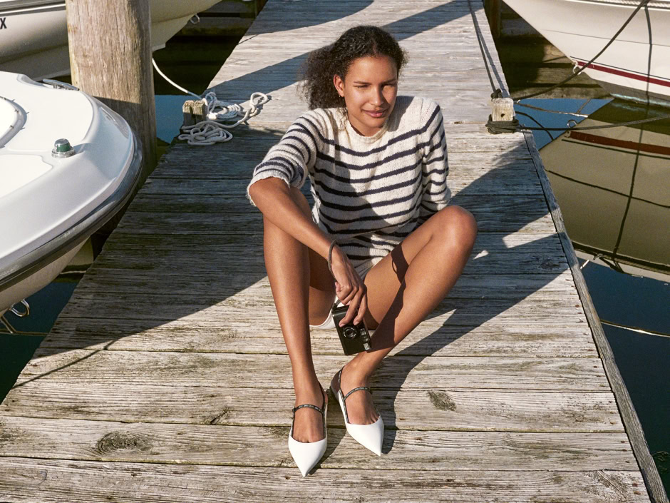 Bohemian women sitting on a rustic wooden dock by sailboats, capturing a relaxed outdoor atmosphere and nautical lifestyle.
