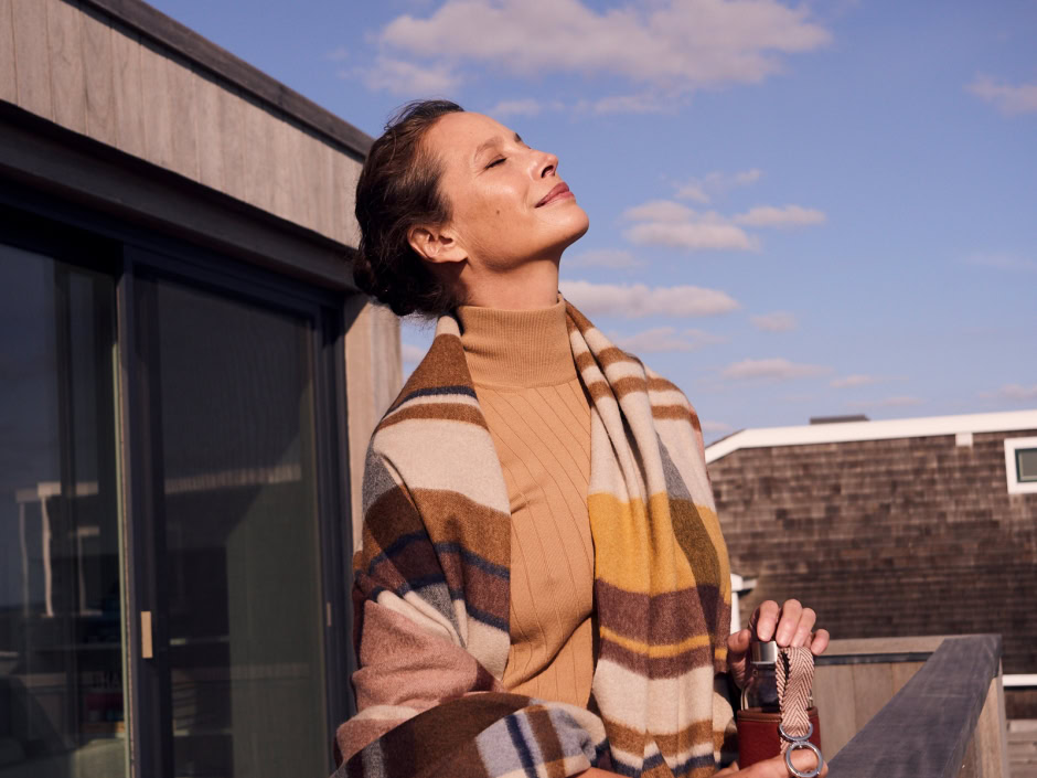Elegant woman enjoying sunshine on rooftop with clear blue sky, showcasing fashion photography and natural outdoor portrait photography by Pamela Hanson.